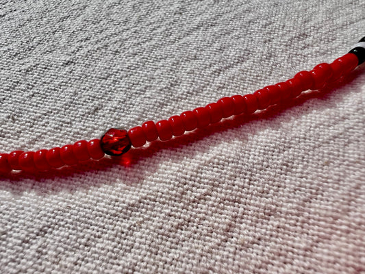 Handmade beaded bracelet with red glass seed beads and a faceted red glass bead on linen, elsket