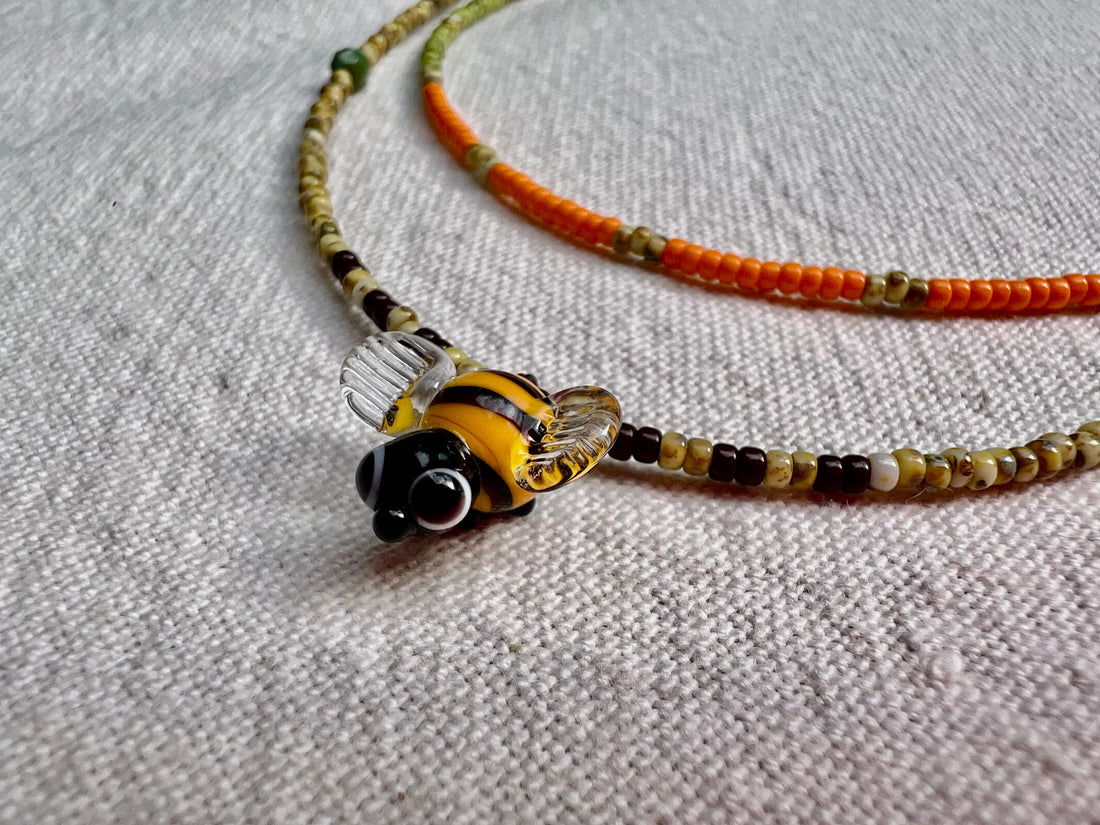 Handmade bee charm necklace with a glass bee pendant on beaded chain on linen, elsket