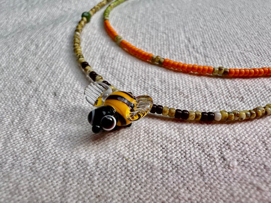 Handmade bee charm necklace with a glass bee pendant on beaded chain on linen, elsket